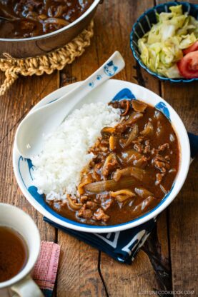 A round shallow bowl containing a bed of steamed rice and Hayashi Rice.