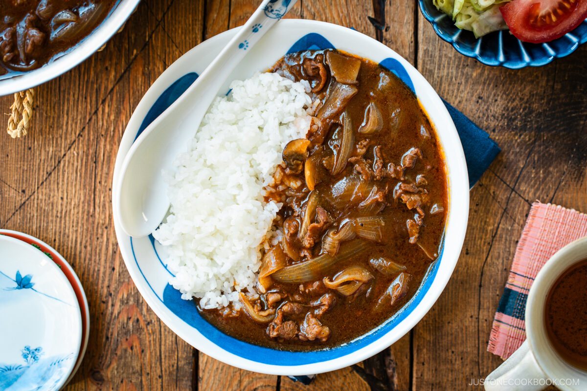 A round shallow bowl containing a bed of steamed rice and Hayashi Rice.