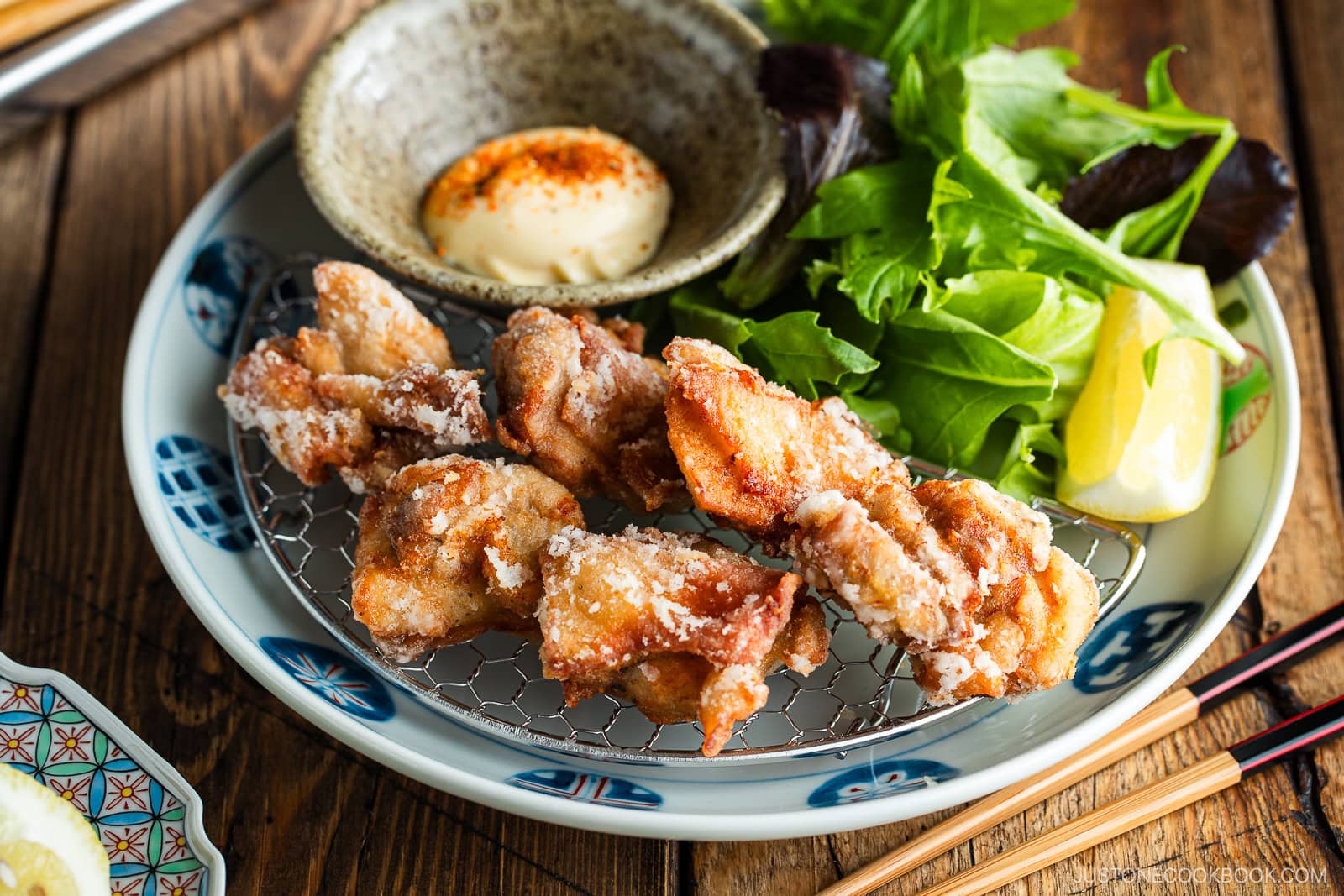 Beautiful Japanese plates containing karaage, Japanese fried chicken, garnished with lemon wedges and kewpie mayo dollop sprinkled with shichimi togarashi.