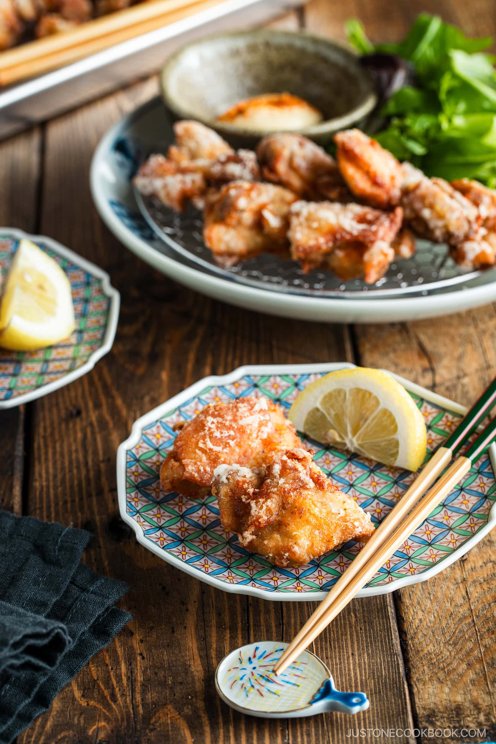 Beautiful Japanese plates containing karaage, Japanese fried chicken, garnished with lemon wedges and kewpie mayo dollop sprinkled with shichimi togarashi.