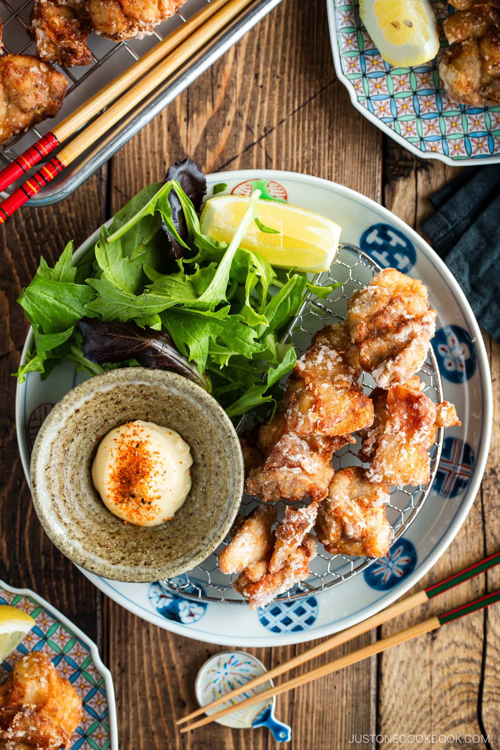 Beautiful Japanese plates containing karaage, Japanese fried chicken, garnished with lemon wedges and kewpie mayo dollop sprinkled with shichimi togarashi.