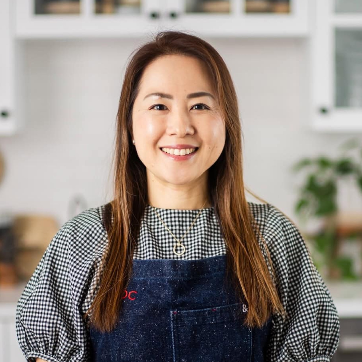 Fresh-faced woman smiling in a cozy kitchen, showcasing Japanese home cooking and recipes featured on Fancy Foods Show, with a warm and inviting atmosphere.