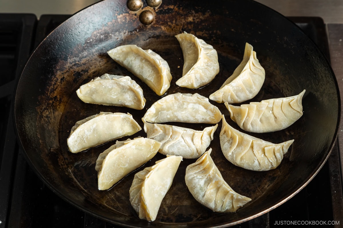 Arrange the gyoza in a circle pattern in a frying pan.