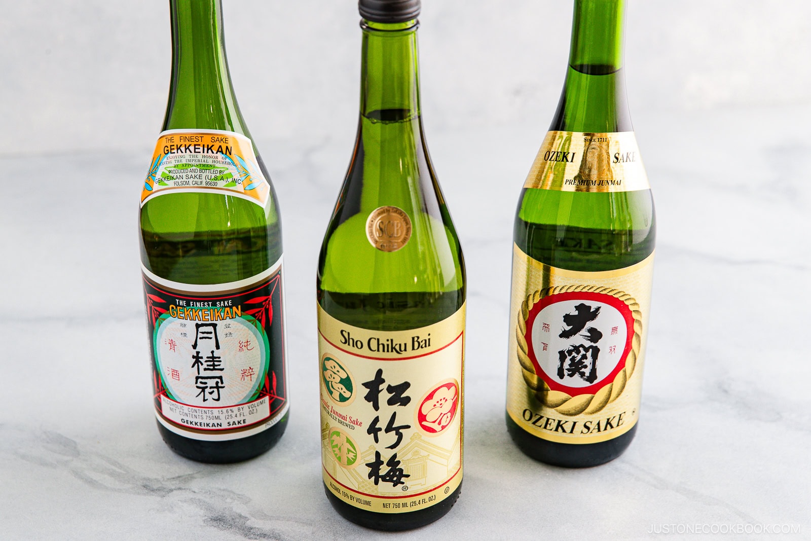 Three bottles of sake stand on a light gray surface, each with a unique label: Gekkeikan, Sho Chiku Bai, and Ozeki Sake&mdash;perfect for exploring Sake vs Mirin: Key Differences and How to Use Them in your cooking or tasting.